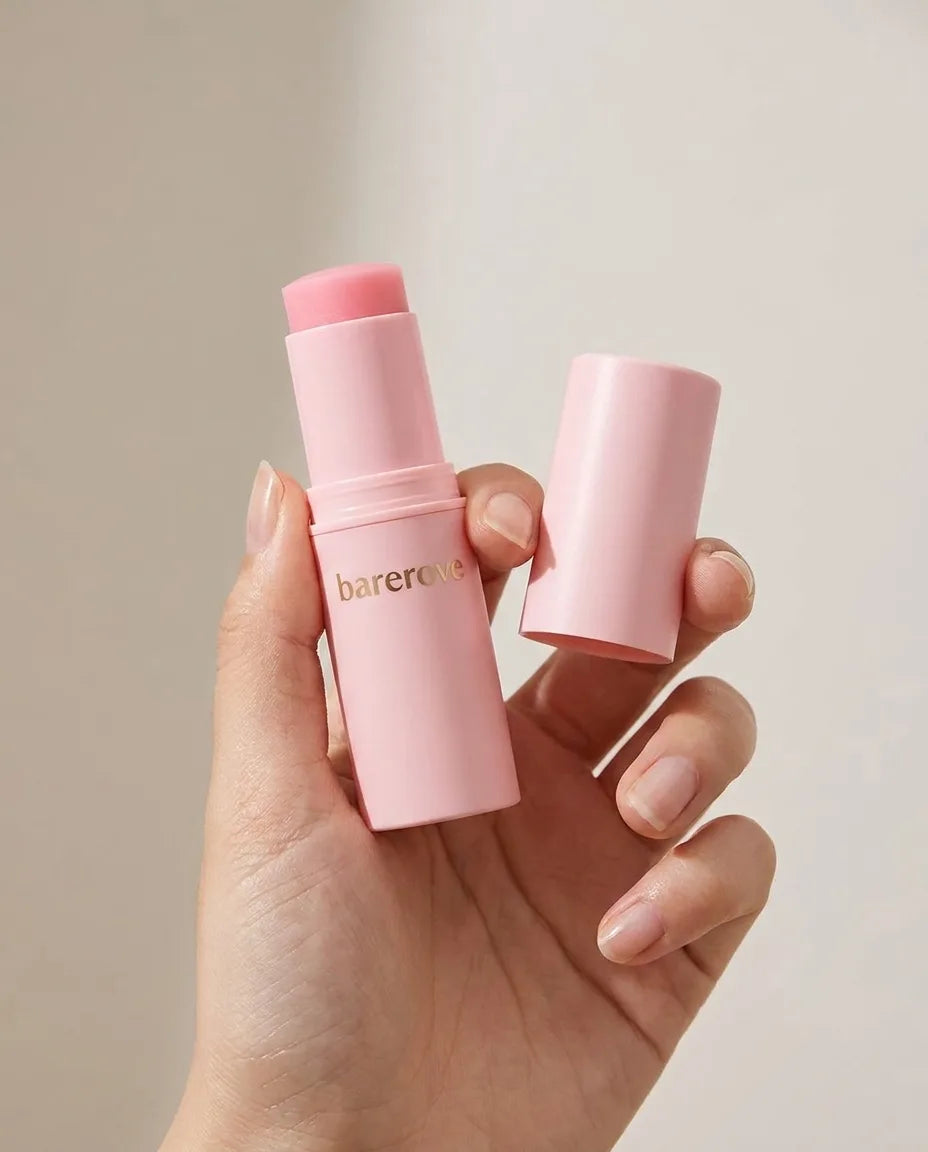 The slim pink balm stick held between two fingers to show its real size